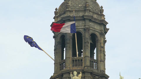 Flags of EU and France hanging on top of historical building, waving in the wind