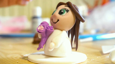 Female hands molds little character from the mastic