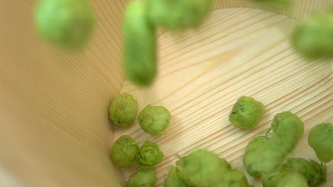Two videos of hops falling into wooden bucket in real slow motion