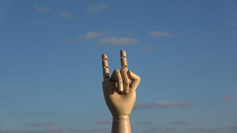 Wooden manikin hand rotating on blue sky background, 4K