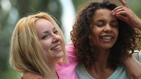 Gay female couple smiling, embracing tightly while posing in front of camera