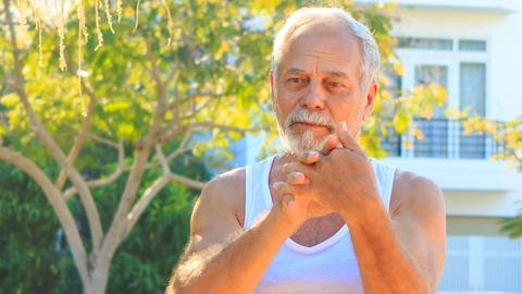 Old Man Does Morning Exercises Stretches Fingers in Park