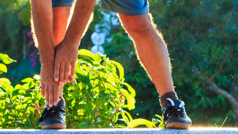 Closeup Man Does Morning Exercises Bends Hands to Foot in Park