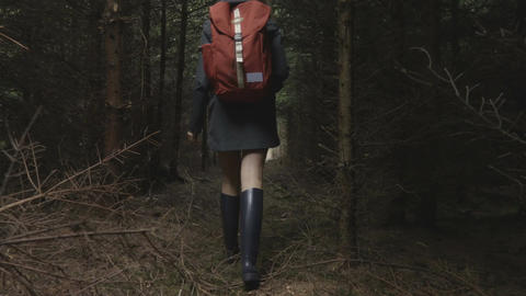 Young woman walk through the dark forest in the evening