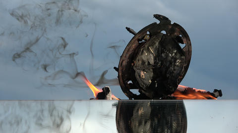 Burning old analogue clock on mirror on sky background