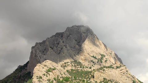Time lapse clouds drift around and over mountain peak, Koba-Kaya Mountain