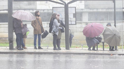 People at bus shelter in heavy rain Coimbra Portugal