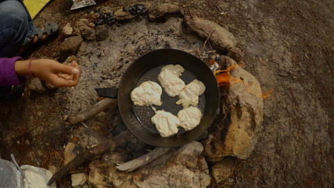 hands holding a frying pan, pancakes roasted on an open fire from above, smoke