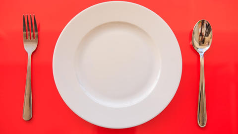 Hands Put Fork Spoon Vertically by Plate on Red Table