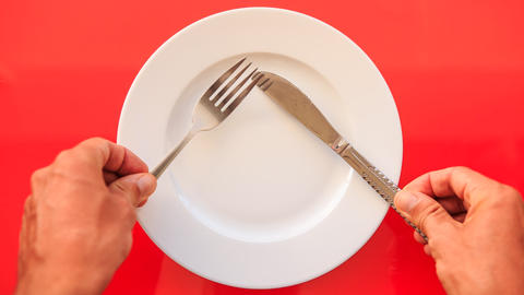 Hands Put Fork Knife at Right Angle on Plate on Red Table
