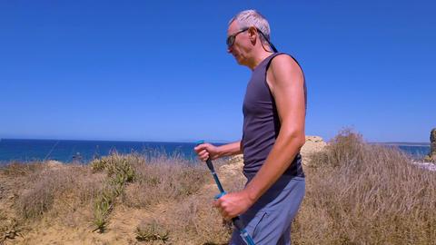 Man Uses Sticks for Scandinavian Walking on the Beautiful Sea Shore