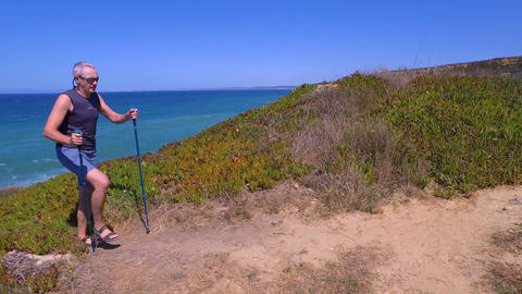 Man Uses Sticks for Scandinavian Walking on the Beautiful Sea Shore