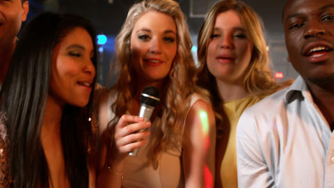 Happy friends singing at the karaoke in night club