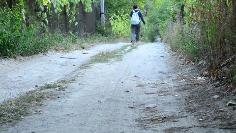 Woman in trousers with backpack walks away from camera