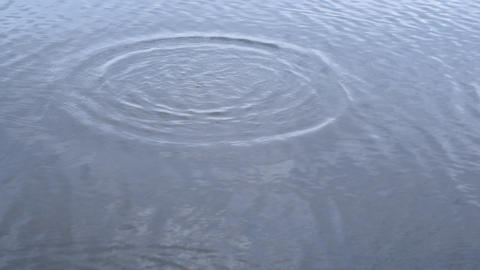 Stone falls into water producing rings and waves on water surface