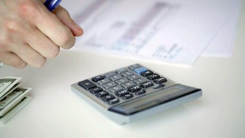 close up of man with calculator counting money
