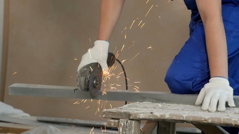 Industrial worker cutting metal with many sharp sparks at construction site