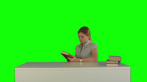 Female student reading a book for finding information on a Green Screen
