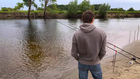 Fisherman with a fishing rod on the river bank. Man fisherman catches a fish