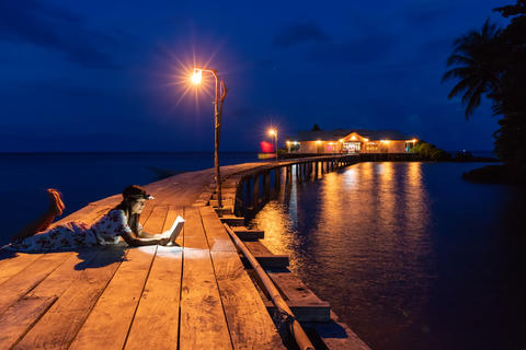 Woman reading book on a wooden pier at night