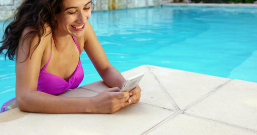Smiling woman relaxing on pool and using smartphone