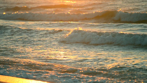 Rays of the setting or rising sun with sea waves on the shore close up