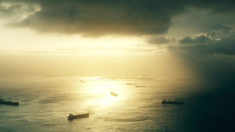 Time lapse of cargo ships and oil tankers at sea at stormy sunset as seen from