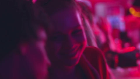 Young couple flirt on date after having drinks at night club bar during party