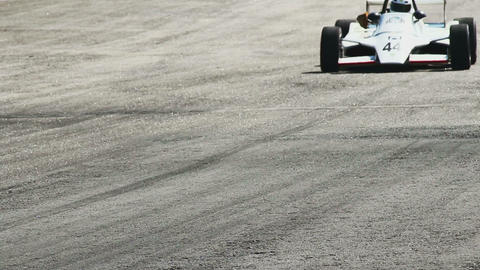 Formula 1 car passes by hot racing track tarmac