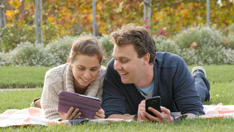 Happy attractive young couple using mobile wireless technology devices