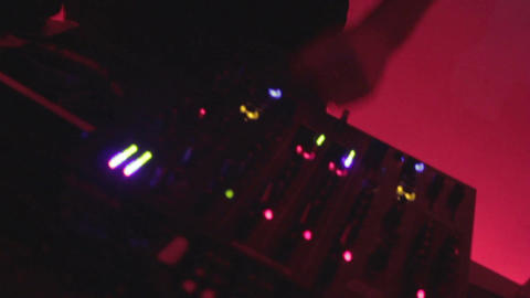 Zoom out dj's hands tweaking controls, playing record in club