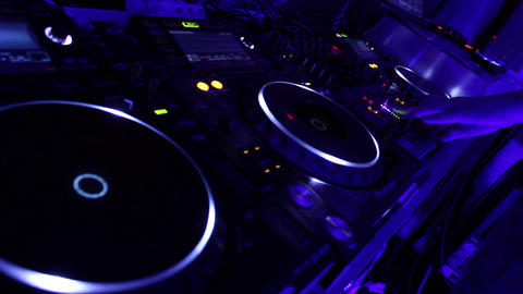 Dj spinning platter on turntable, tweaking controls on the deck