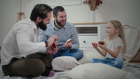 Little girl with her dads having fun with donuts