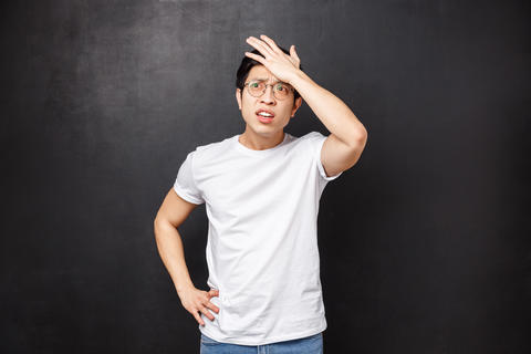 Forgetful embarrassed young asian male student forgot to write essay for next