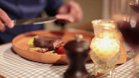 Elegant man eating grilled meat and drinking wine in restaurant