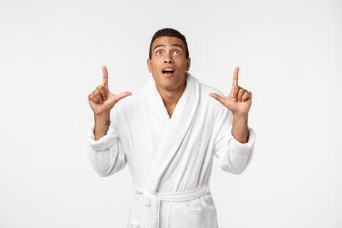 African american guy wearing a bathrobe pointing finger with surprise and happy