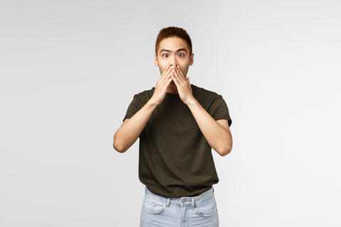 Surprised and amused asian man gasping, cover mouth and look camera impressed