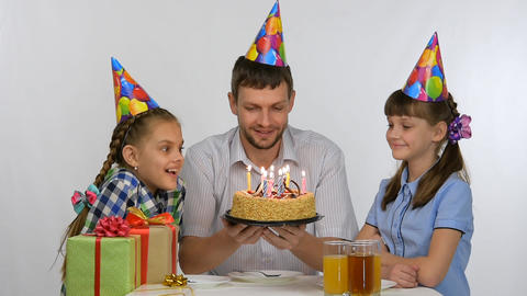Dad shows children a birthday cake with candles