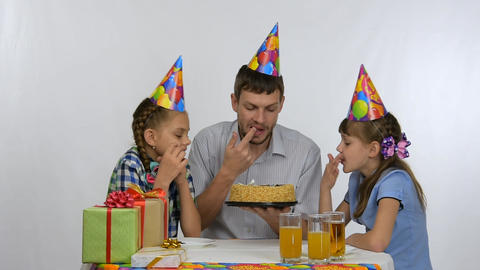 Kids and dad have fun biting a birthday cake
