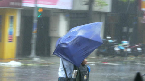 Pedestrian struggles to cross street in typhoon wind and rain