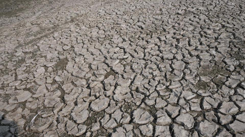 Panning shot of dry cracked clay soil, drought