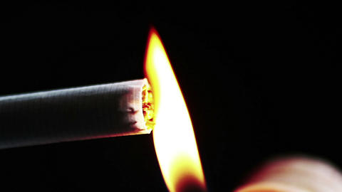 man lights up a cigarette with lighter on black background complete smoke