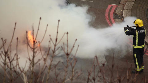 Fire fighters putting out a car fire following an accident