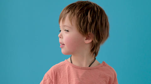 Little boy shakes head in disbelief at bright turquoise wall