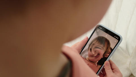 Little child plays with video filter on smartphone at home