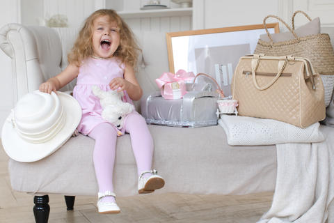 Happy little girl playing with a retro suitcase