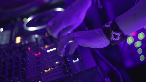 Male DJ holding console buttons, playing music at party in popular night club