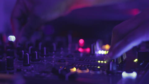 DJ hands pushing buttons on the mixing console. Night club atmosphere. Party