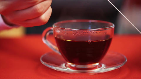 Process of preparing black tea. Woman pressing teabag with the help of spoon