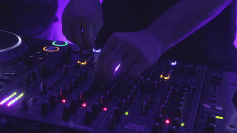 Go-go dancer moving to music behind disk jockey during performance at party